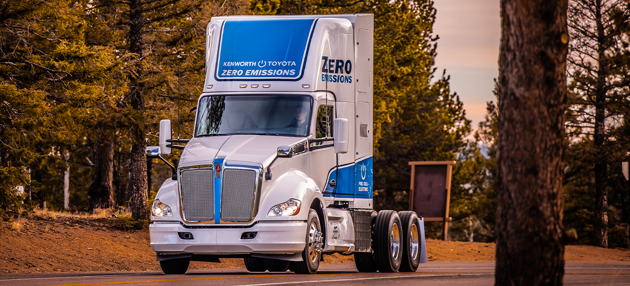 Kenworth T680 electric parked in the background with trees in foreground